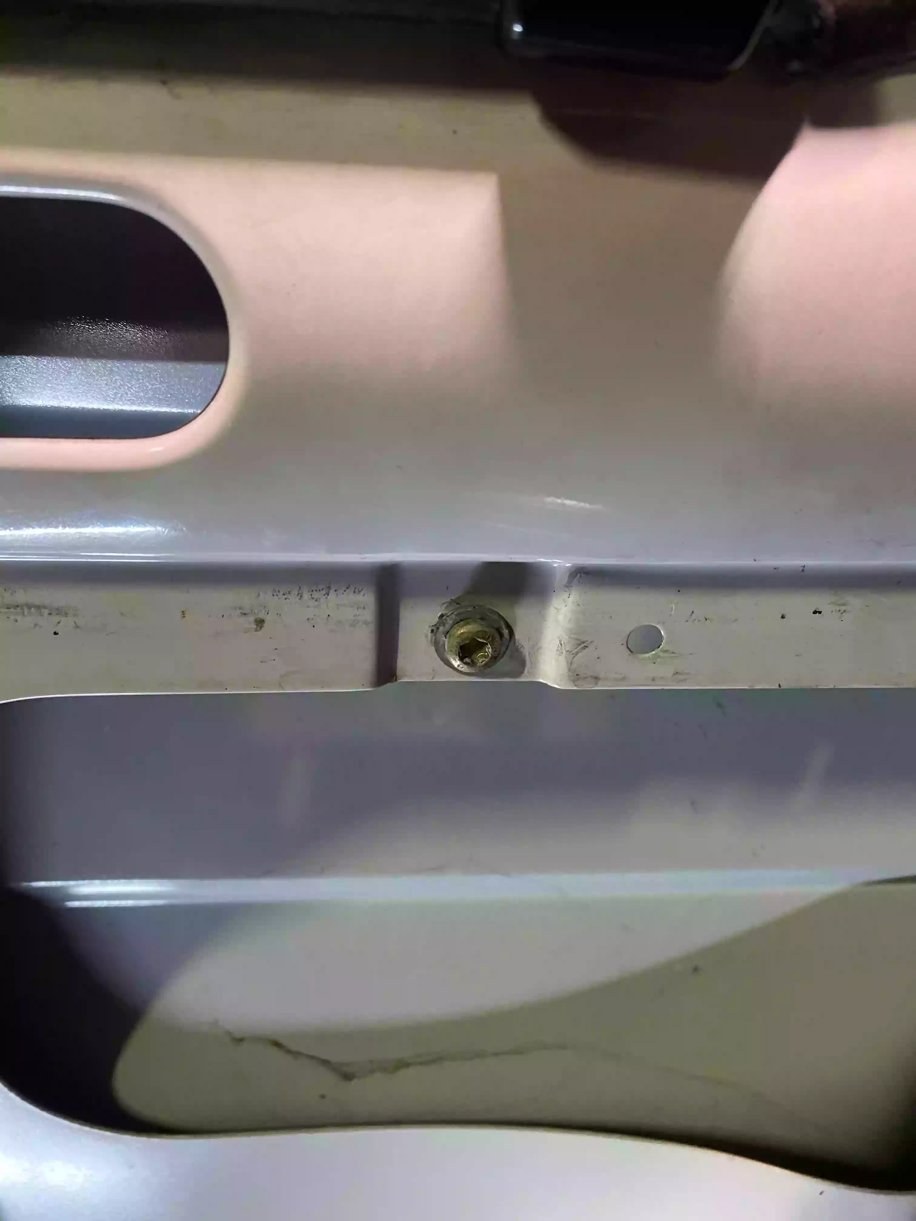 Le boulon se situant en dessous de l'emplavement de la poignée de porte intérieure